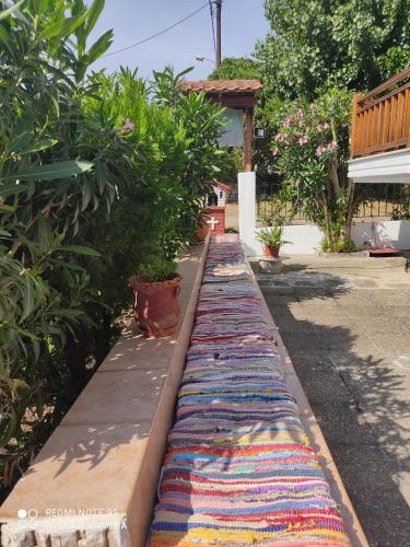 a row of colorful rugs are lined up on a sidewalk at Kastalia in Ammouliani