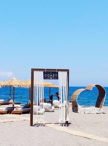 a sign on a beach with chairs and umbrellas at The Coast seaside rooms in Anaxos
