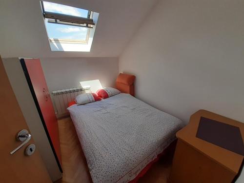a small bedroom with a bed and a skylight at Apartman kod autobuske in Bijeljina