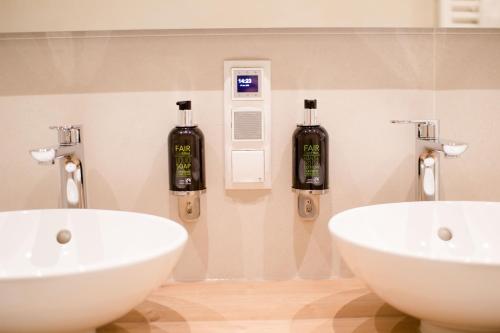 two sinks in a bathroom with two bottles on the wall at Studio Apartments Opera - Mai's Apartments - by Arbio in Vienna