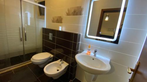 een badkamer met een wastafel, een toilet en een spiegel bij Dair Ghbar Apartment in Amman