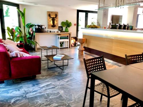 un soggiorno con divano rosso e tavoli di Appart' Hotel La Girafe Marseille Est - Porte d'Aubagne a La Penne-sur-Huveaune