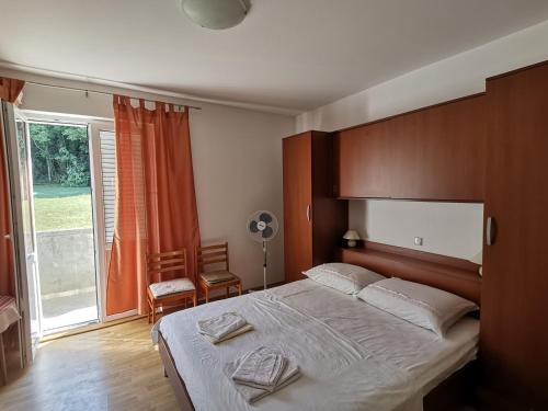 a bedroom with a large bed and a large window at Apartmani Škarić in Lopar