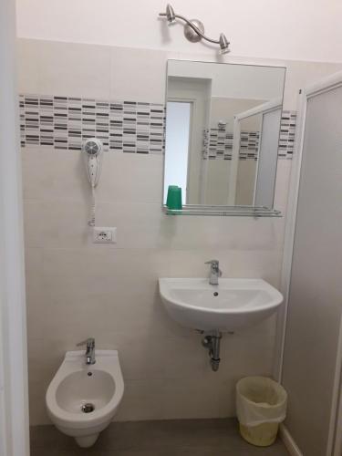 a bathroom with a sink and a toilet and a mirror at Hotel Real in Cesenatico