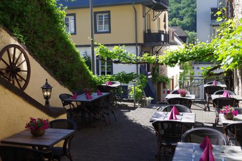 an outdoor patio with tables and chairs and a building at Gast und Weinhof Beim Schneemann in Valwig