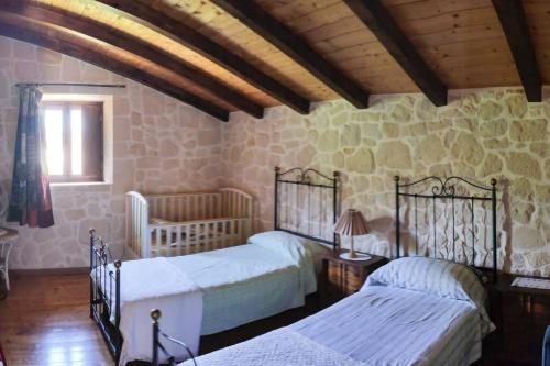 Un dormitorio con dos camas y una pared de piedra. en Villa Neli, Palazzolo Acreide, Siracusa, Hot Tub, Wi-Fi & Parking, en Palazzolo Acreide
