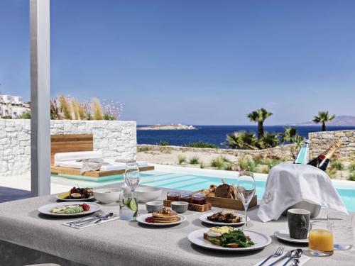 stół z talerzami jedzenia obok basenu w obiekcie Mykonos Earth Suites w mieście Mykonos
