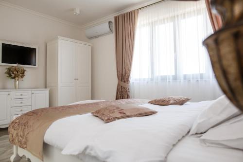 a bedroom with a white bed and a window at Pensiunea Carpe Diem Spa in Dumbrăviţa