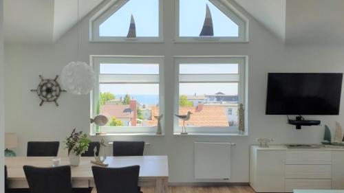 a dining room with a table and a tv and two windows at Urlaubsdomizil InselLust-Rügen in Sassnitz