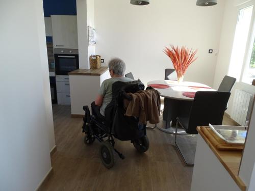 a man in a wheelchair sitting at a table in a kitchen at Le Panorama - Vue mer in Criel-sur-Mer