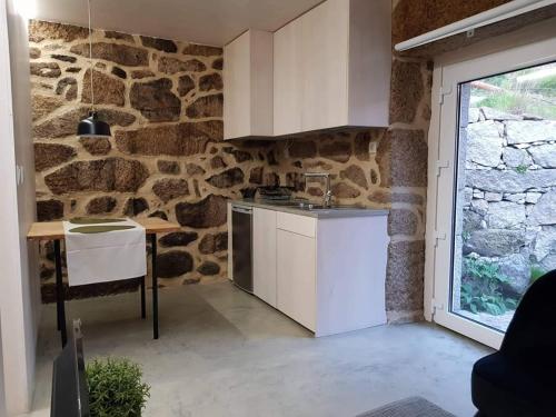 cocina con pared de piedra y armarios blancos en Casa do Doutor Palheiro, en Travassos