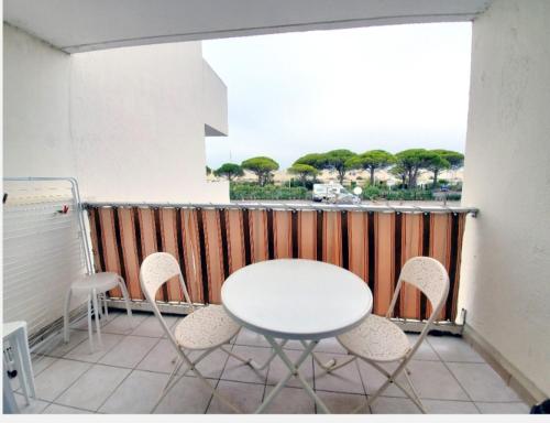 a white table and chairs on a balcony at Studio cabine le grau du roi 6 min de la plage à pied in Le Grau-du-Roi