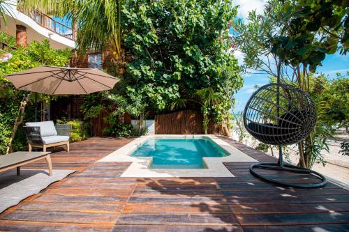 a swimming pool with an umbrella and a chair and a table at Spirit Holbox in Holbox Island
