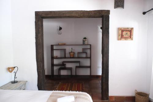 a bedroom with an open doorway with a bed and a shelf at The Wild Olive Andalucía Agave Guestroom in Casares