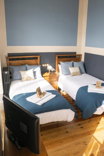 a bedroom with two beds with a tv and a desk at La Venta de Miyares - Casa de Indianos in Piloña