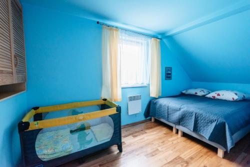 a blue bedroom with a bed and a window at Abramówka - dom z sauną in Polańczyk