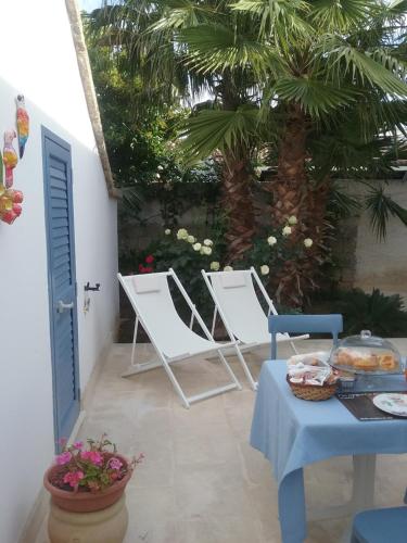 a patio with two chairs and a table and a palm tree at LI CURTI B&B in Melissano