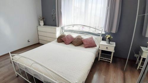 a bedroom with a white bed with pillows on it at Sea&Wine Apartamenty Darłówko in Darlowko