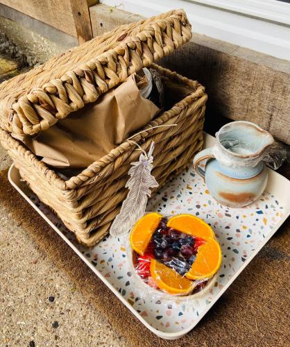 a basket with a plate of fruit and a pitcher at Kwetu Cabin in Bordon