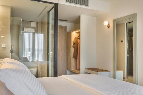 a bedroom with a white bed and a walk in closet at Ionian Plaza Hotel & Spa in Argostoli