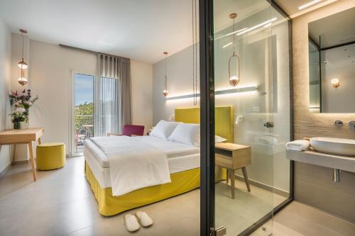 a bedroom with a bed and a bathroom with a sink at Ionian Plaza Hotel & Spa in Argostoli