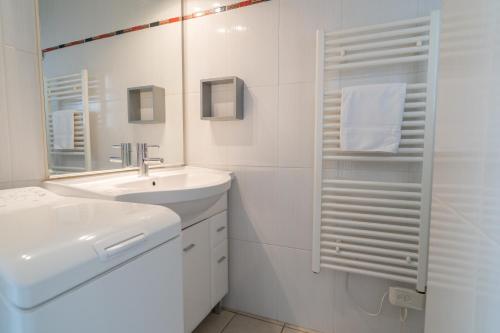 La salle de bains blanche est pourvue d'un lavabo et d'un miroir. dans l'établissement Résidence Lou Cout, à Vieux-Boucau-les-Bains