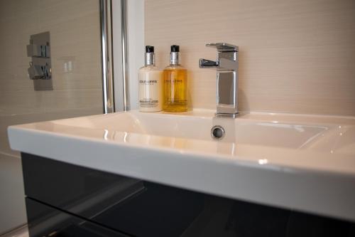 two bottles of alcohol sitting on a bathroom sink at Apple Tree Bed and Breakfast in Tavistock