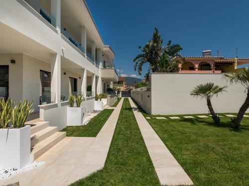 a house with a yard with grass and palm trees at Palazzo Michelangelo in Villasimius