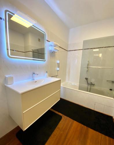 une salle de bain avec un lavabo, une baignoire et un miroir dans l'établissement Grand T2 STANDING AJACCIO Proche centre et plages VUE PANORAMIQUE PARKING PRIVE, à Ajaccio