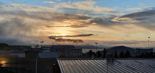 a sunset over a city with the sun in the clouds at Luxury Loft Apartment Akureyri in Akureyri