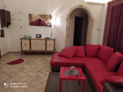 een woonkamer met een rode bank en een tafel bij La casa nel borgo in Acaya
