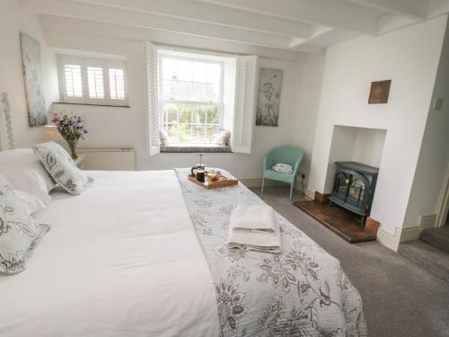 a bedroom with a large white bed and a fireplace at 1 Belle Vue in Osmotherley