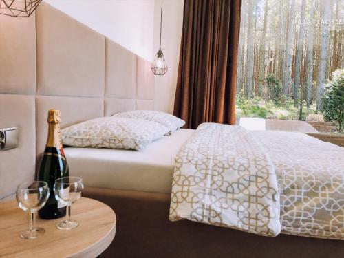 a bedroom with a bed and a bottle of wine at Willa Zacisze - Ostrowo - Komfortowe Apartamenty i Pokoje w cichej okolicy - Oaza spokoju in Ostrowo