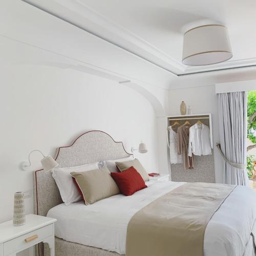 a white bedroom with a large bed with red pillows at Villa Fortuna in Positano