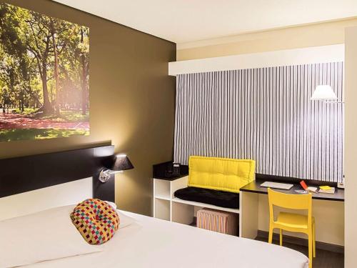 Habitación con cama y escritorio con silla amarilla. en Ibis Styles Porto Alegre Centro en Porto Alegre