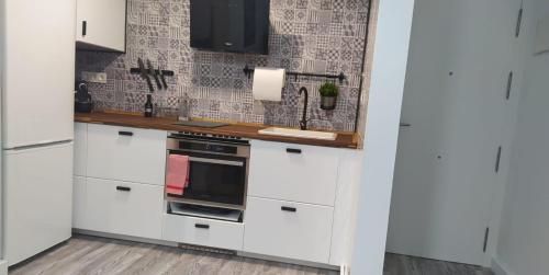 a kitchen with white cabinets and a black oven at Apartamento Dos mares I in La Manga del Mar Menor