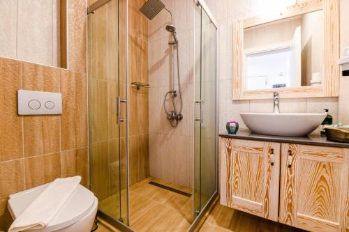 a bathroom with a glass shower and a sink at Kybele Suites in Kaş