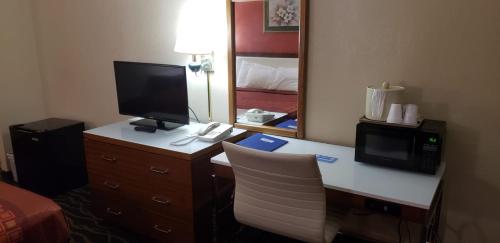 a hotel room with a desk with a computer and a television at Rodeway Inn Wormleysburg – Harrisburg in Harrisburg