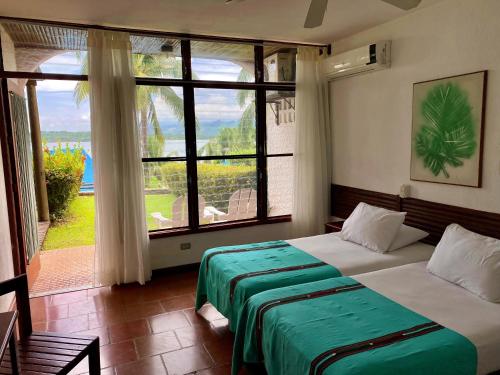 a bedroom with a bed and a large window at Villa Caribe in Lívingston