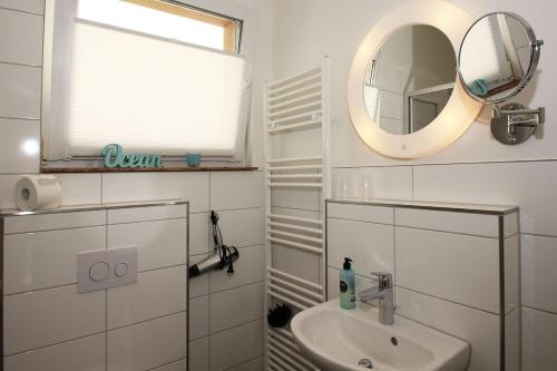 a white bathroom with a sink and a mirror at F-1093 Villa Elise Ferienwohnung Nr 01 in Göhren