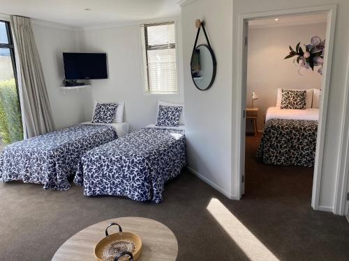 a room with two beds and a chair and a mirror at Alpine Lake Motel in Taupo