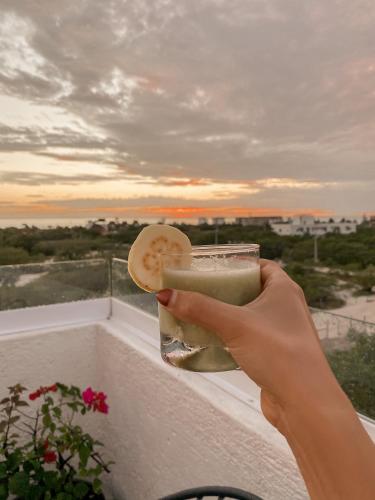 a person holding a drink in a glass on a balcony at Hotel Casa HX - Adults Only in Holbox Island