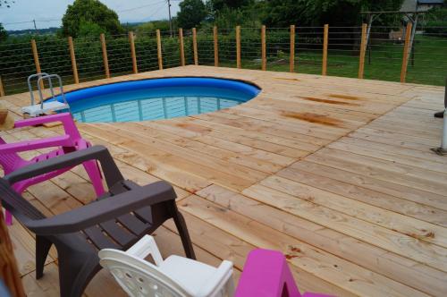 a wooden deck with a swimming pool and chairs at Gîte de 15 places en chambre de 2, 4, 5 personnes in Saint-Exupéry-les-Roches