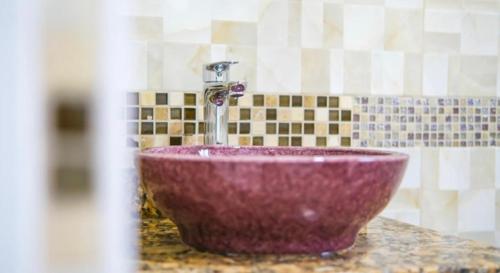 um lavatório roxo com uma torneira na casa de banho em Royal Bliss Apartment Suites em Kingstown