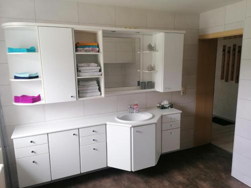 a white bathroom with a sink and a mirror at Ferienwohnung Waldblick mit Balkon in Sebnitz