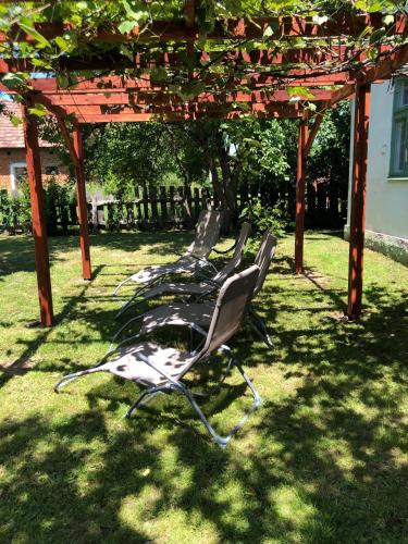 a row of chairs sitting under a pergola at Cseri Porta Kisház in Szatta