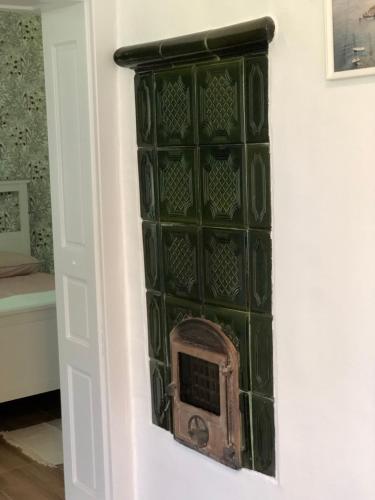 a green glass wall with a fireplace in a room at Cseri Porta Kisház in Szatta