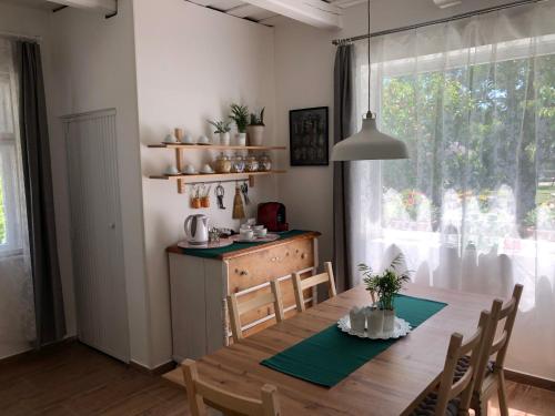 a dining room with a table and chairs and a window at Cseri Porta Kisház in Szatta