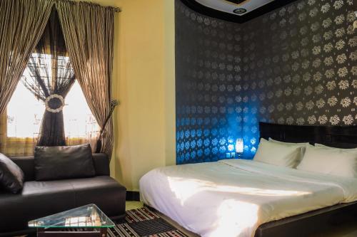 a bedroom with a bed and a chair and a window at Arabian Lodges in Bahawalpur