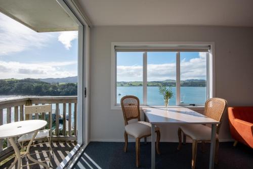 a dining room with a table and chairs and a large window at Mangonui Motel in Mangonui